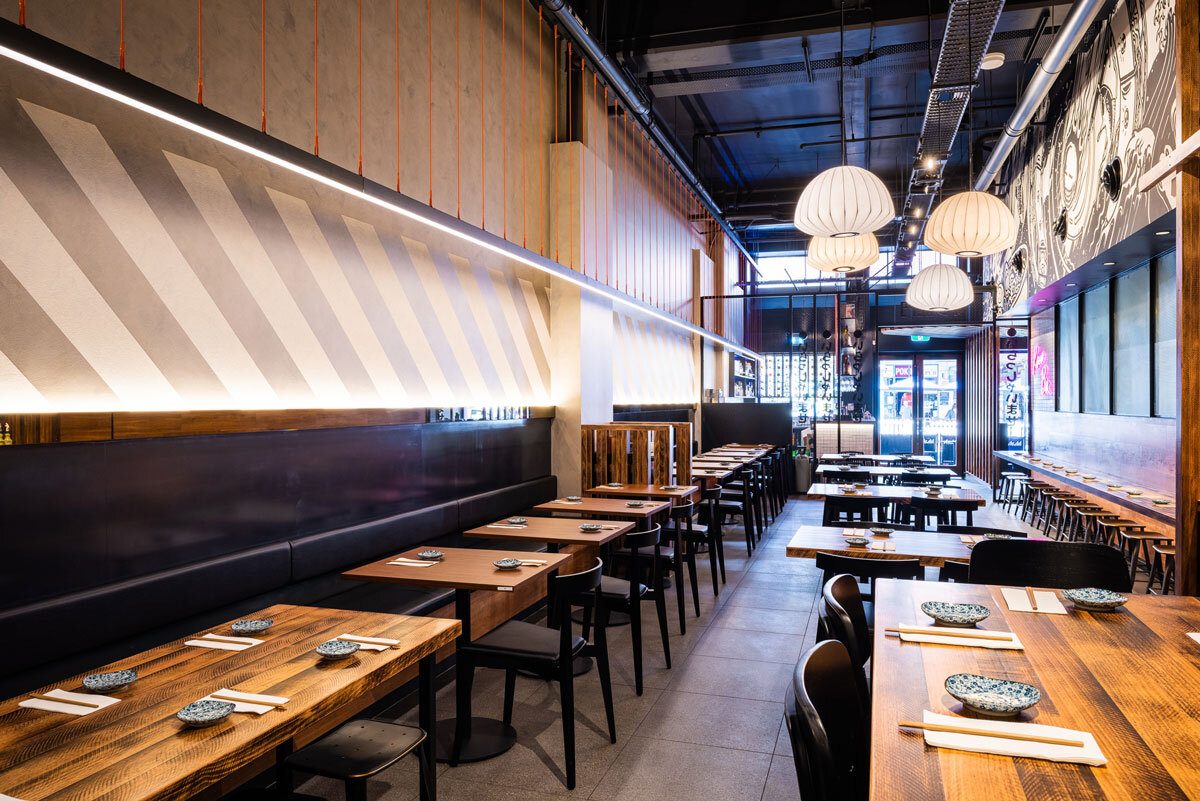 The dining room: striped timber wall, paper lanterns and long tables